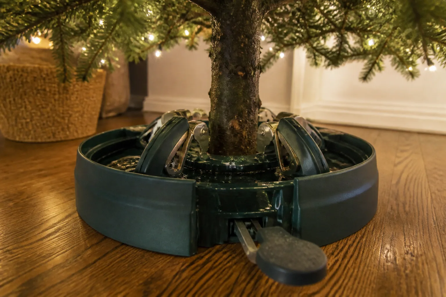 Foot-pedal Christmas tree stand claws gripping a trunk in a water-filled basin