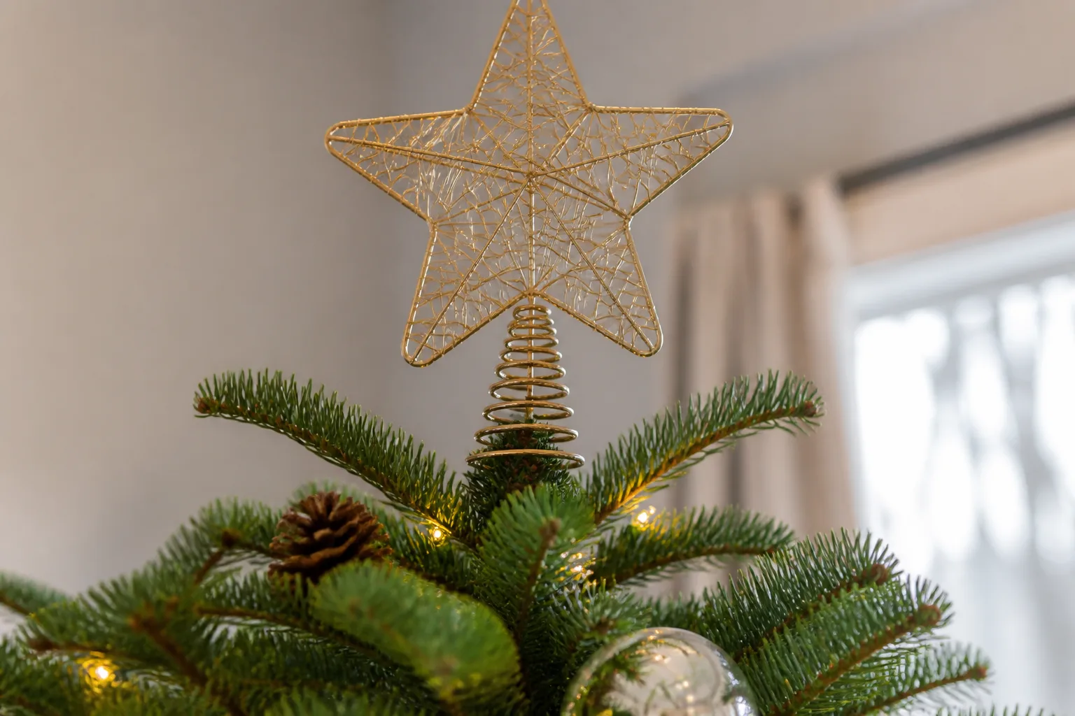 Gold wire star tree topper secured at the tip of a Christmas tree with discreet green florist wire