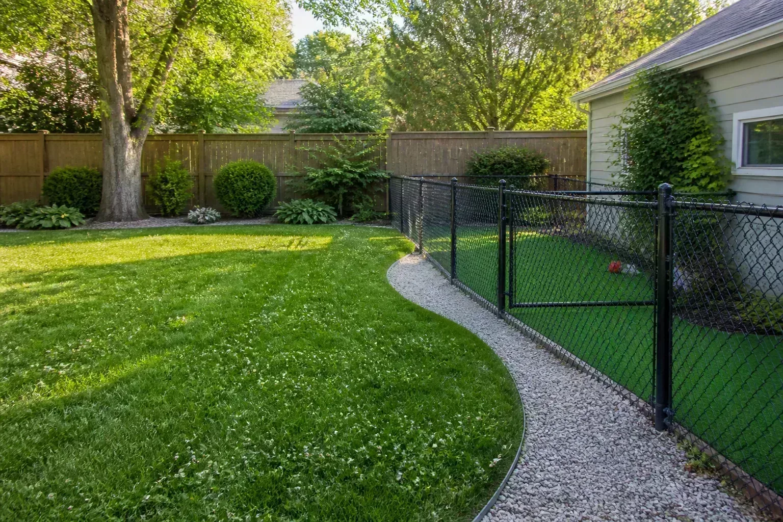 Hybrid backyard with natural clover lawn beside a fenced synthetic turf dog run
