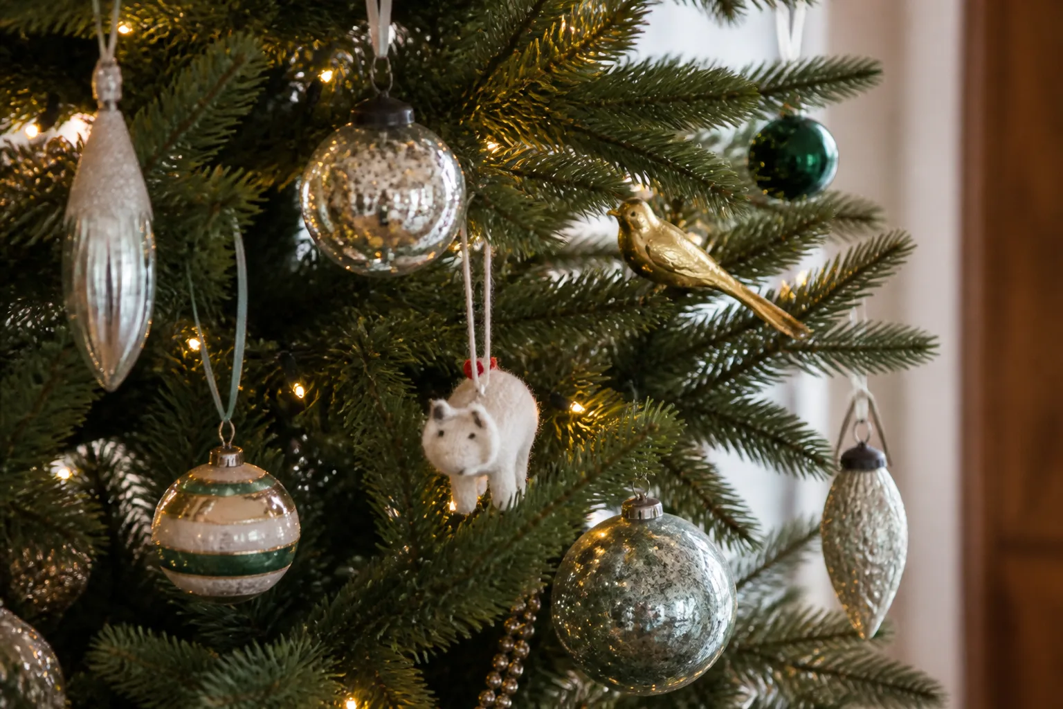 Mixed collected Christmas tree ornaments including mercury glass, vintage finds, and handmade pieces on green branches
